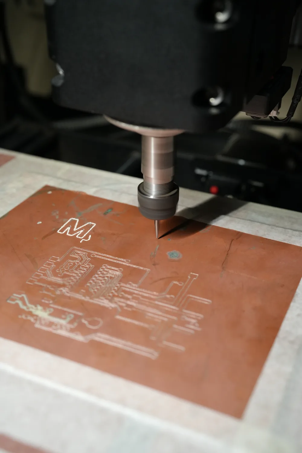 The Forge 3020 routing circuit traces into a copper-clad board